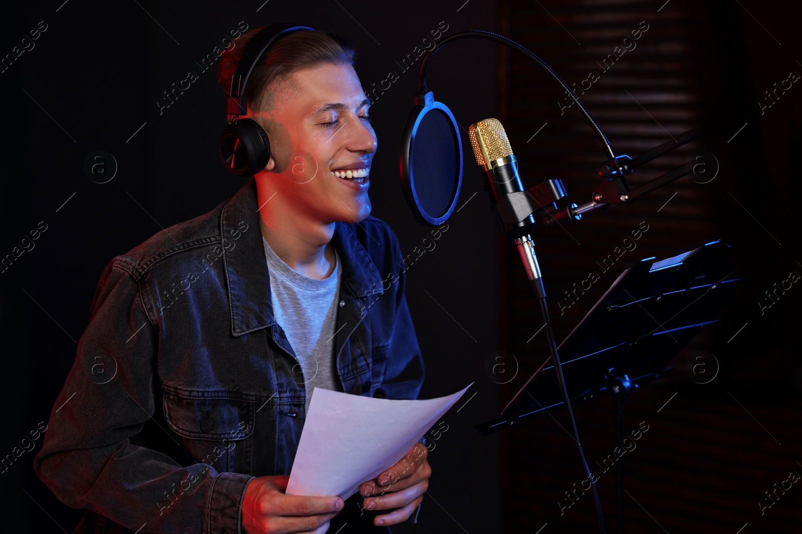 Photo of Singer with sheet recording song in professional studio