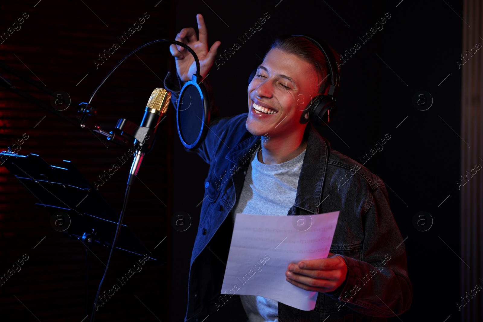 Photo of Singer with sheet recording song in professional studio