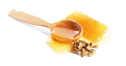 Sweet honeycomb, spoon and propolis granules isolated on white