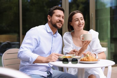 Photo of Happy couple having breakfast in outdoor cafe