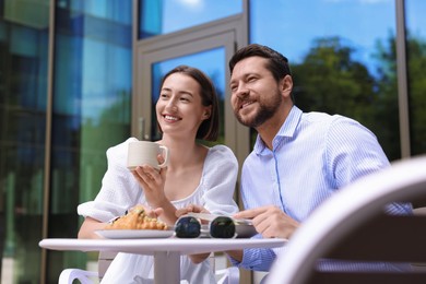 Photo of Happy couple having breakfast in outdoor cafe