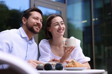 Photo of Happy couple having breakfast in outdoor cafe