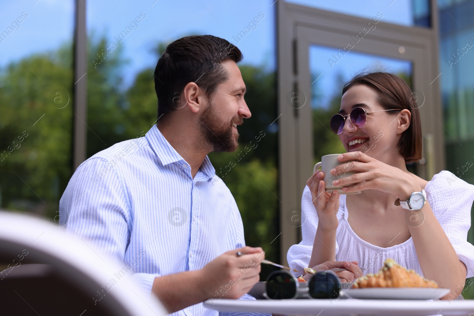 Photo of Happy couple having breakfast in outdoor cafe