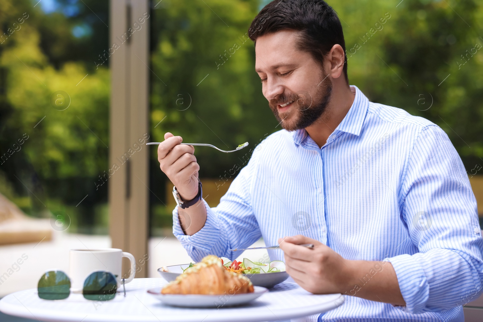 Photo of Happy man having breakfast in outdoor cafe