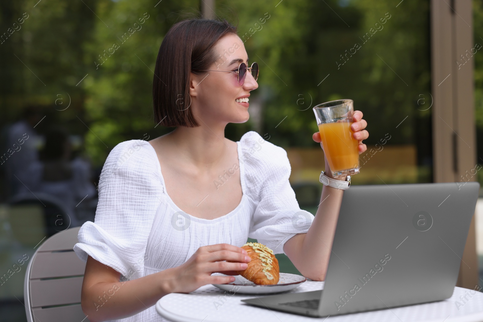 Photo of Happy woman having tasty breakfast in outdoor cafe