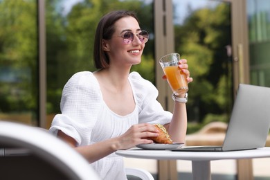 Photo of Happy woman having tasty breakfast in outdoor cafe