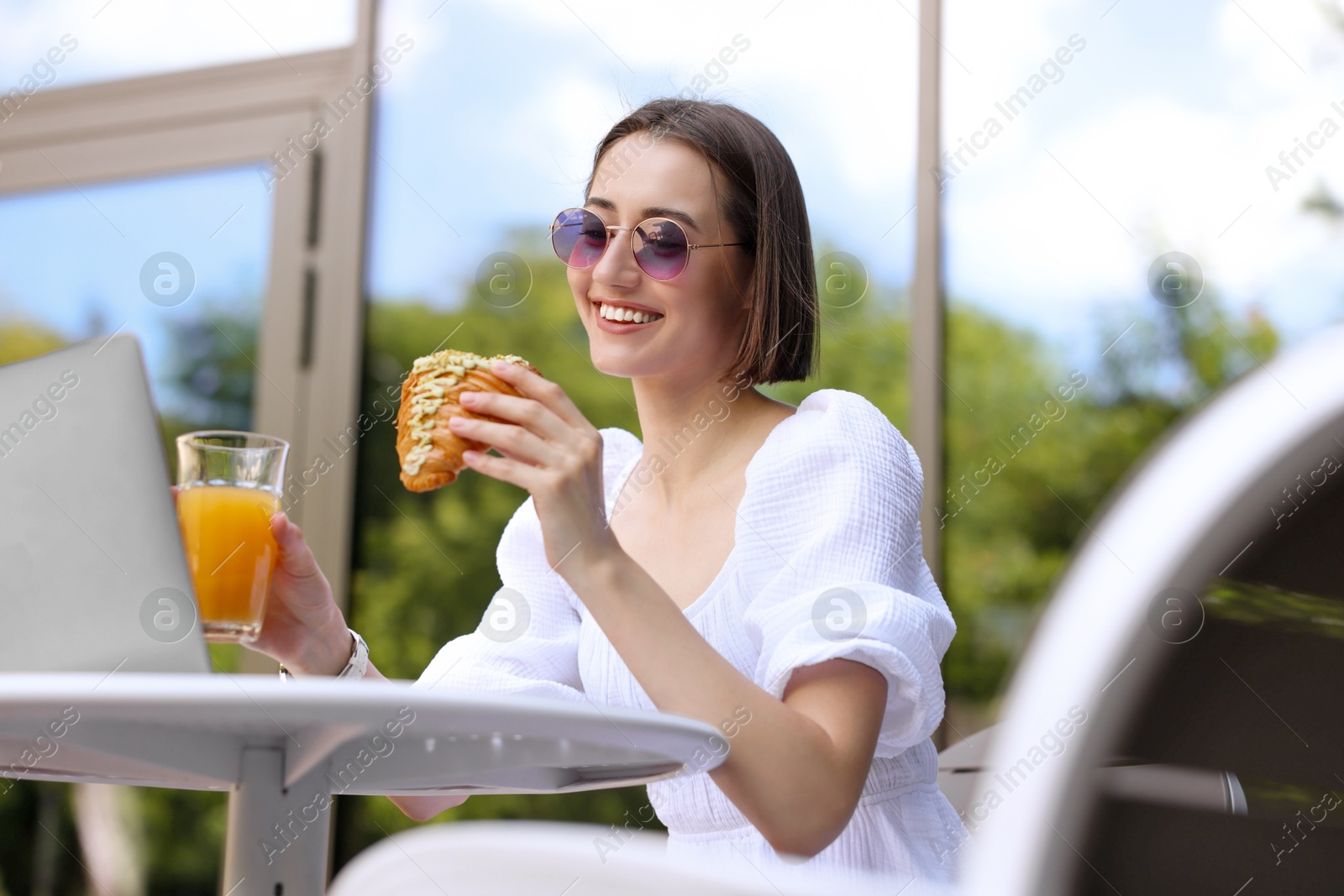 Photo of Happy woman having tasty breakfast in outdoor cafe