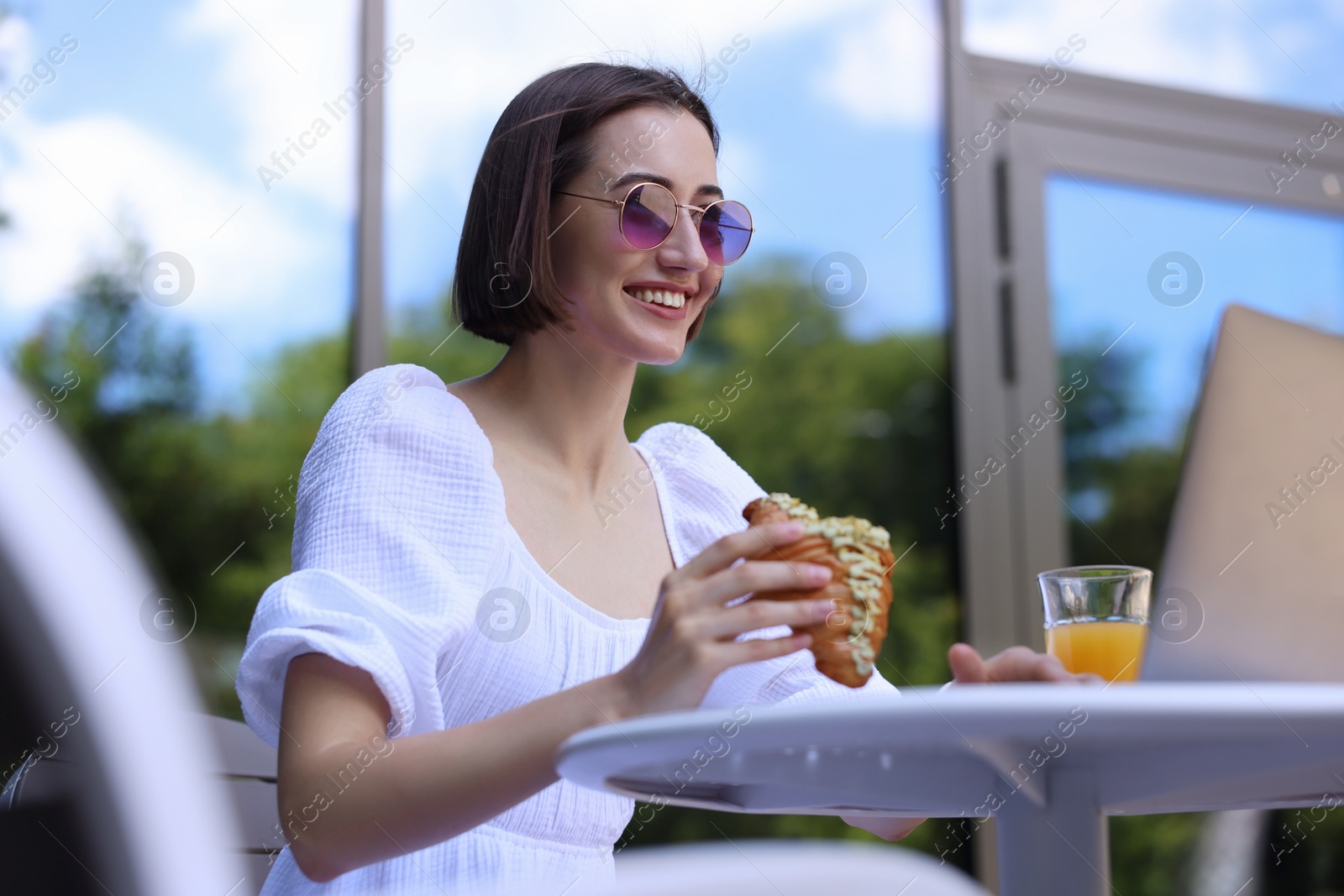 Photo of Happy woman having tasty breakfast in outdoor cafe