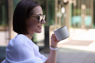 Happy woman having breakfast in outdoor cafe, space for text