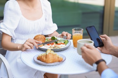 Couple having tasty breakfast in outdoor cafe, closeup