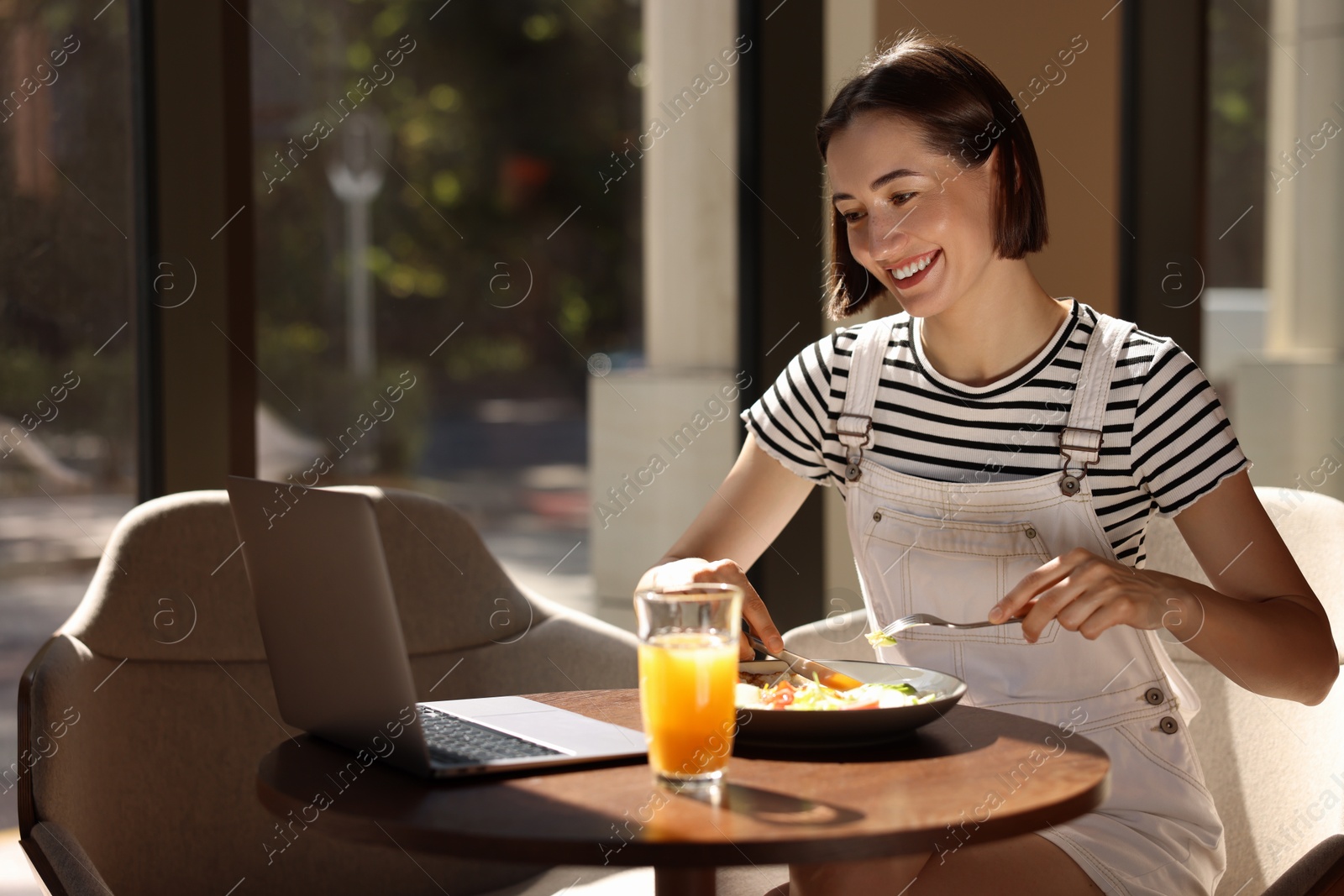 Photo of Happy woman having tasty breakfast in cafe