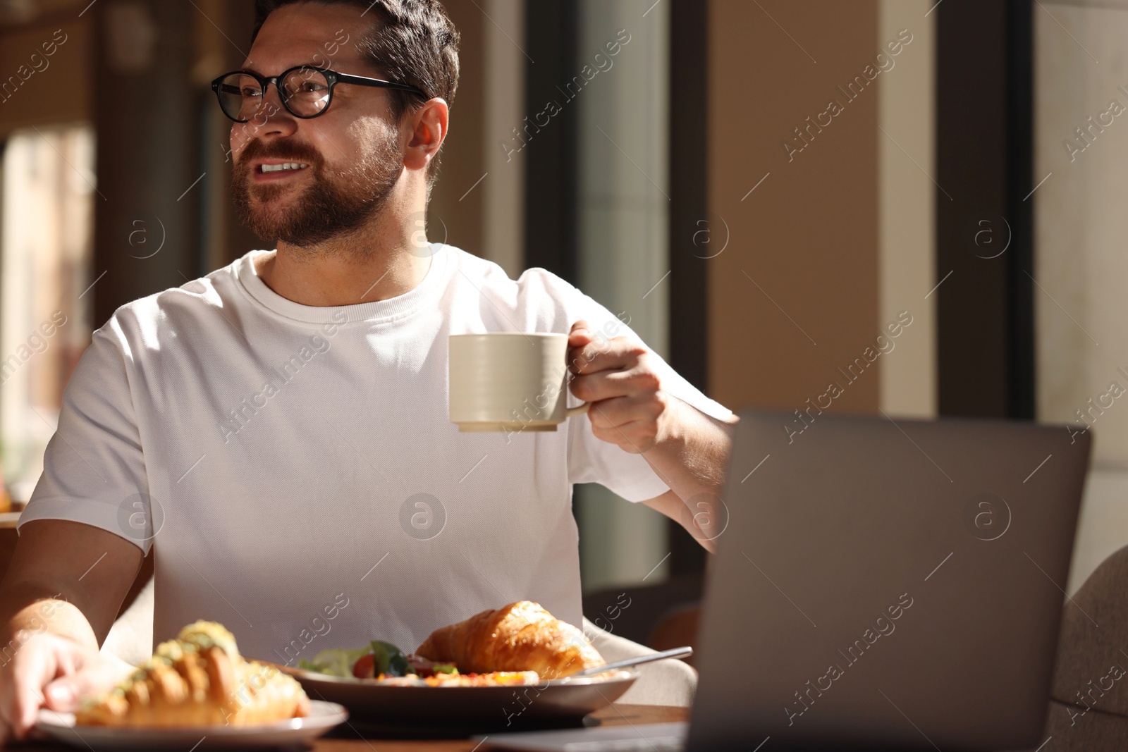 Photo of Happy man having tasty breakfast in cafe