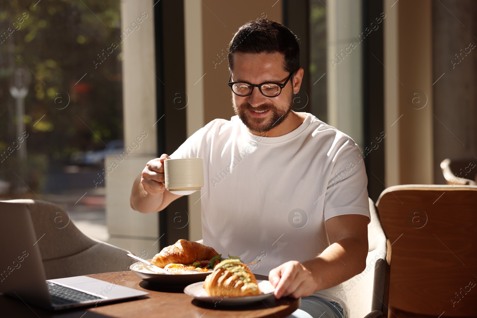 Photo of Happy man having tasty breakfast in cafe