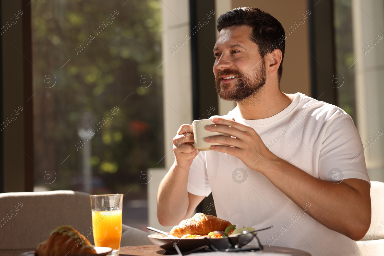 Photo of Happy man having tasty breakfast in cafe