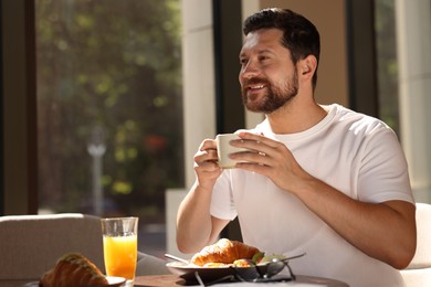 Happy man having tasty breakfast in cafe