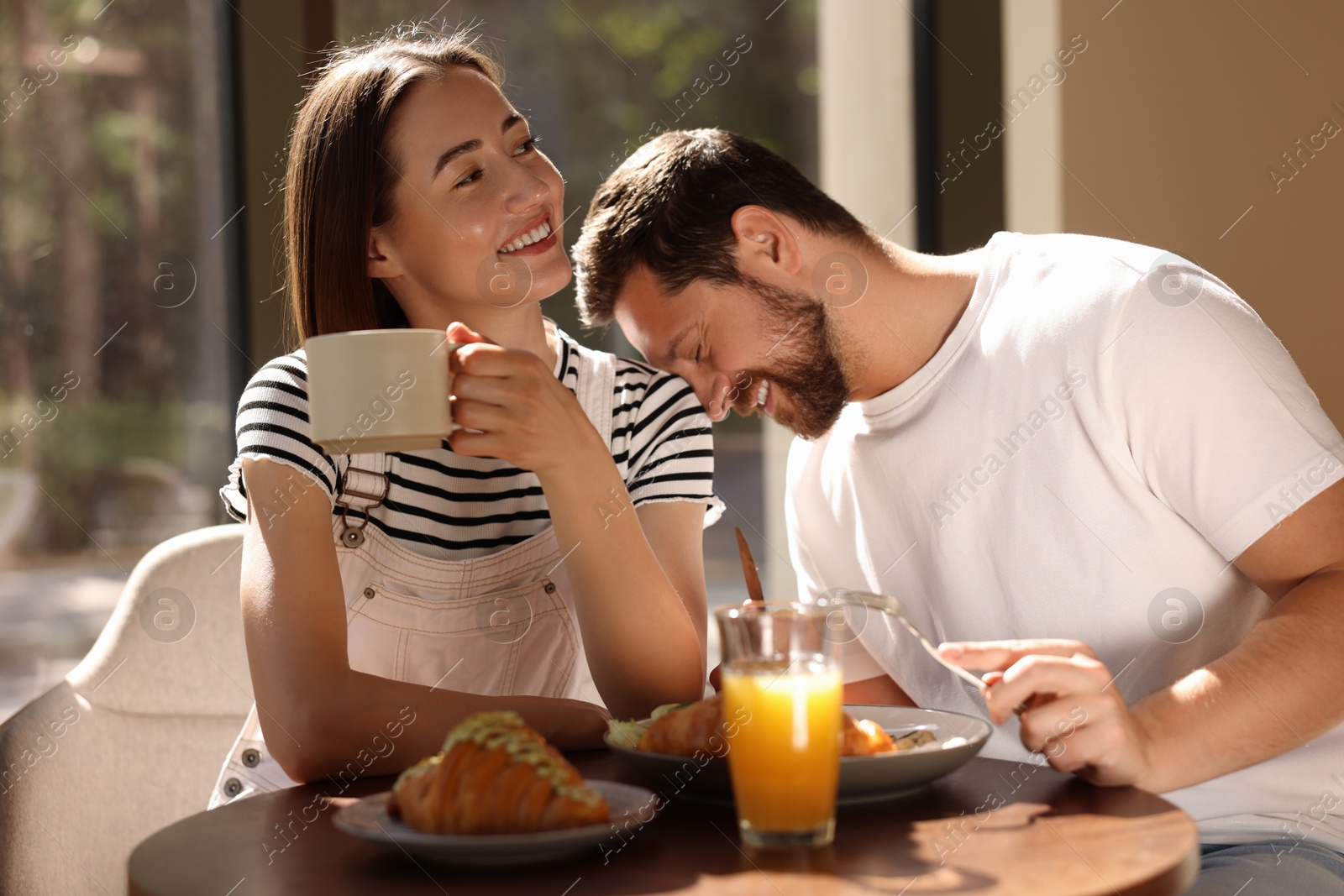 Photo of Happy couple having tasty breakfast in cafe