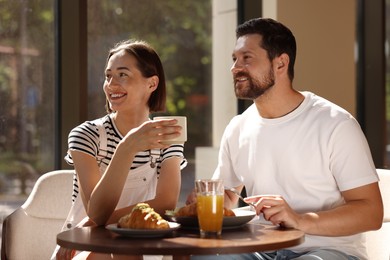 Happy couple having tasty breakfast in cafe