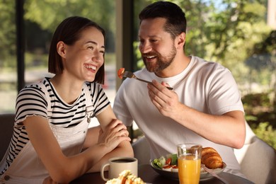 Happy couple having tasty breakfast in cafe