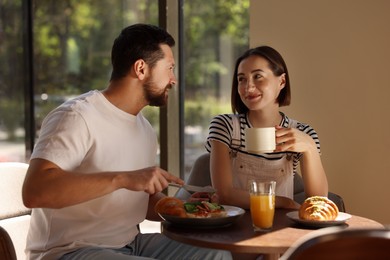 Happy couple having tasty breakfast in cafe