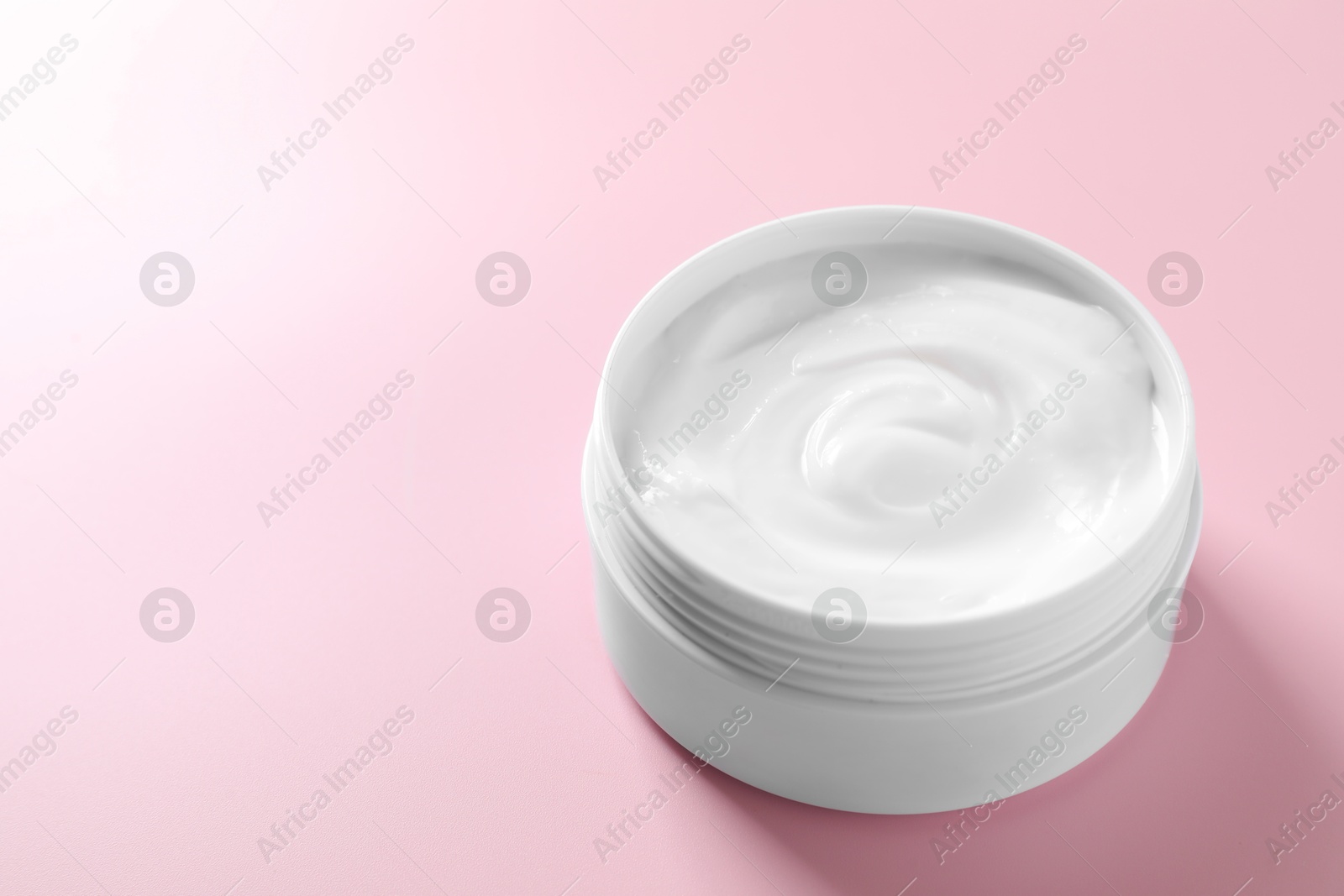 Photo of Face cream in jar on pink background, closeup. Space for text