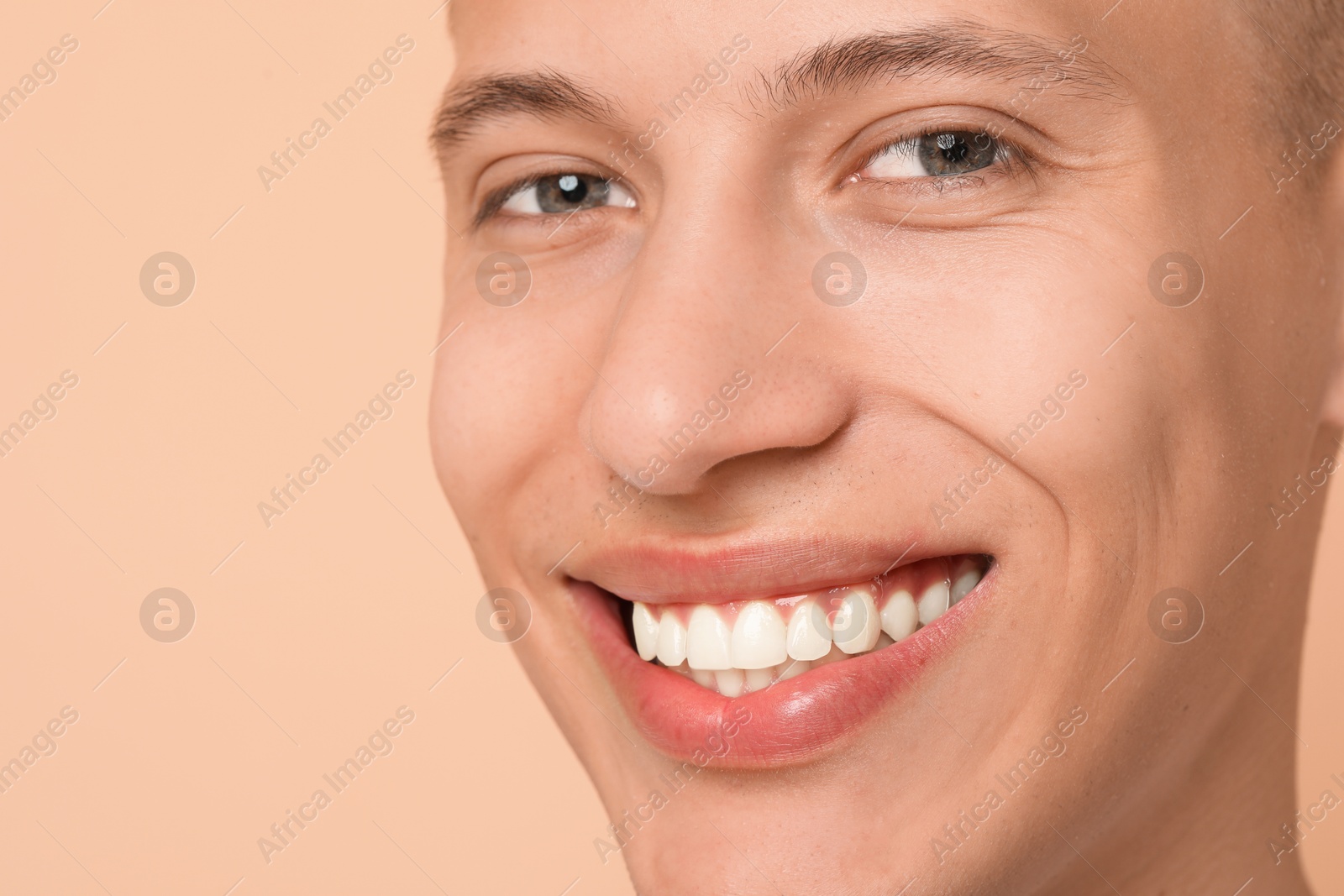 Photo of Happy young man on beige background, closeup. Dental veneers