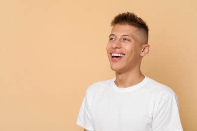 Happy young man on beige background, space for text. Dental veneers