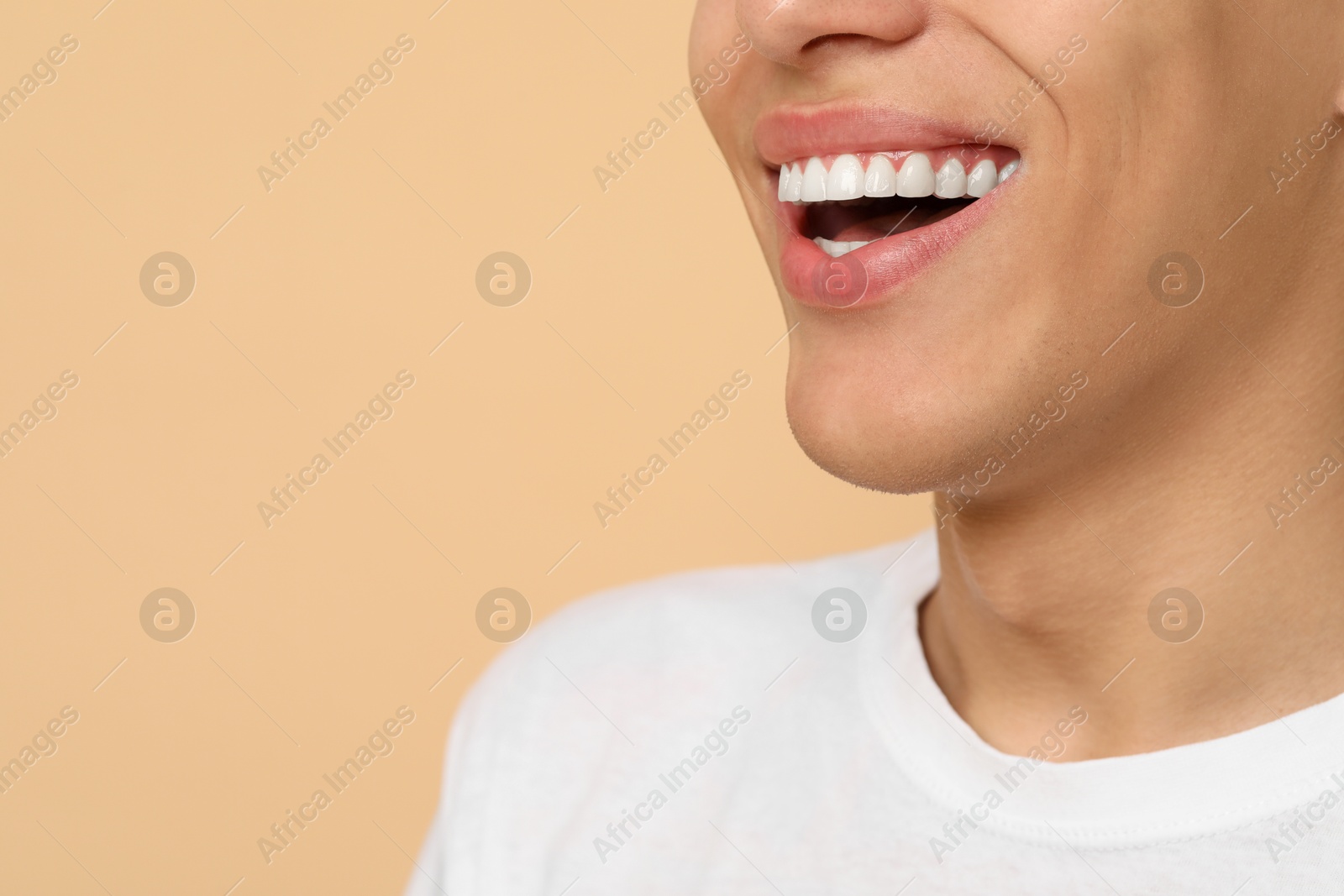 Photo of Happy young man on beige background, closeup with space for text. Dental veneers