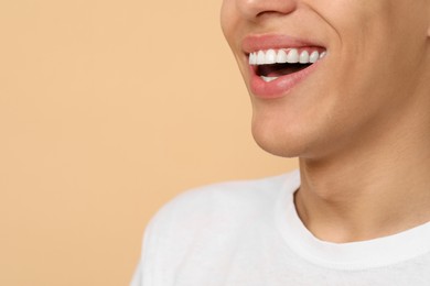 Happy young man on beige background, closeup with space for text. Dental veneers