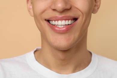 Happy young man on beige background, closeup. Dental veneers