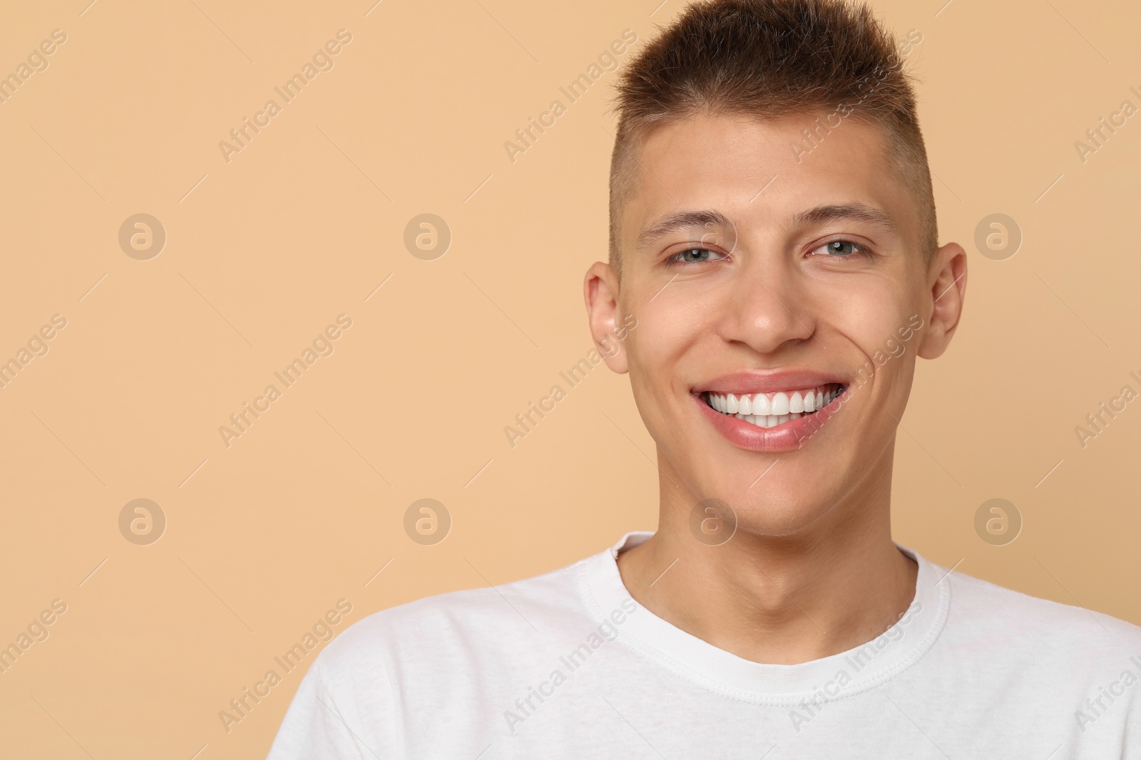 Photo of Happy young man on beige background, space for text. Dental veneers