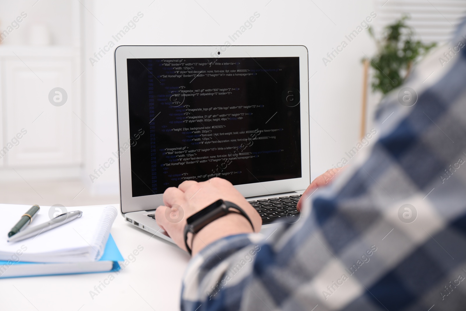 Photo of Programmer working with laptop at white desk in office, closeup