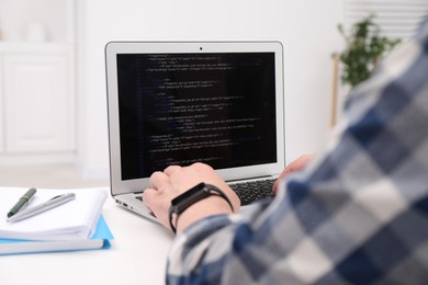 Programmer working with laptop at white desk in office, closeup