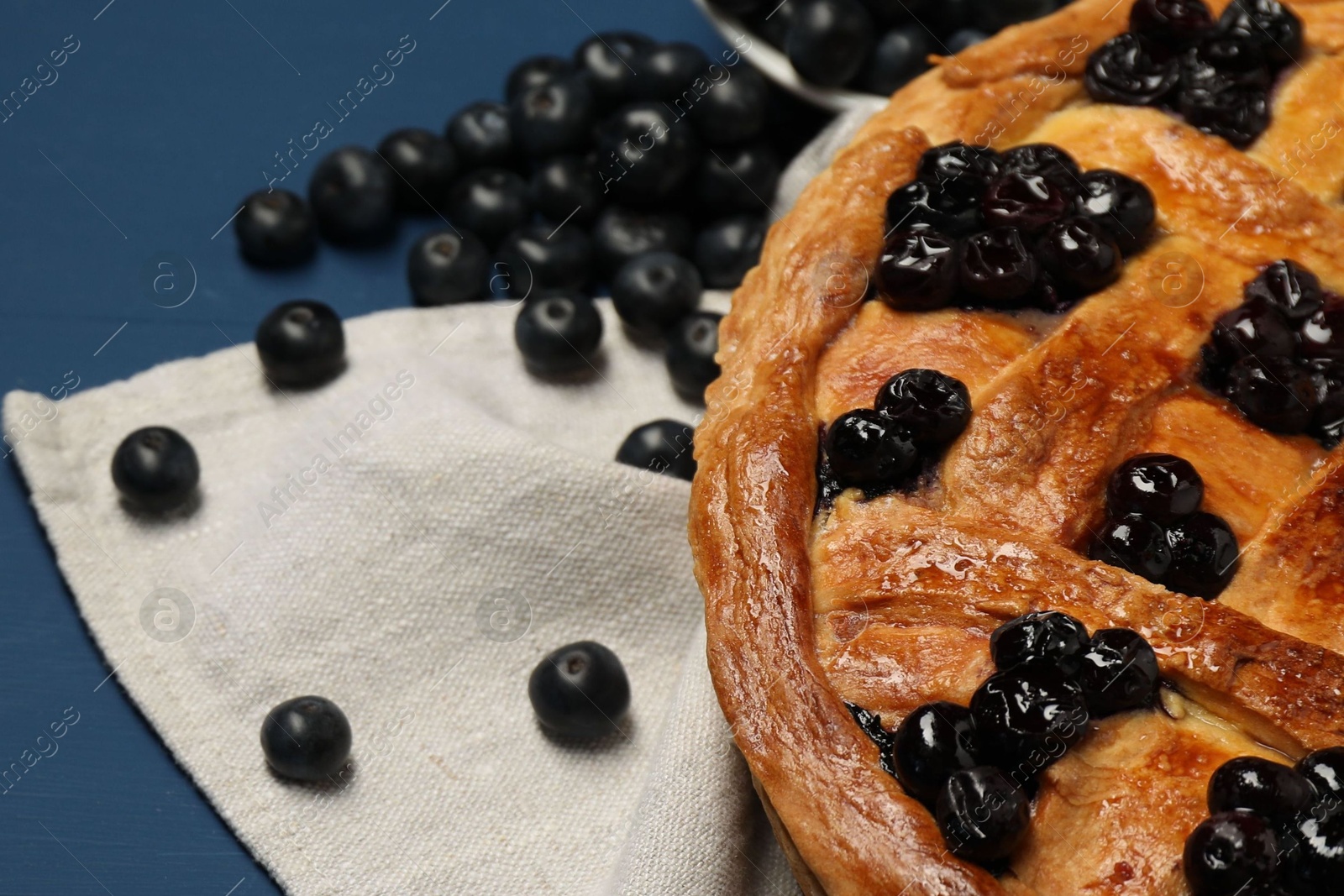 Photo of Tasty homemade pie with blueberries on blue table, closeup. Space for text