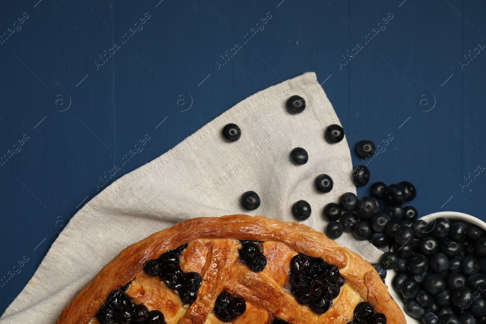 Photo of Tasty homemade pie with blueberries on blue wooden table, flat lay. Space for text