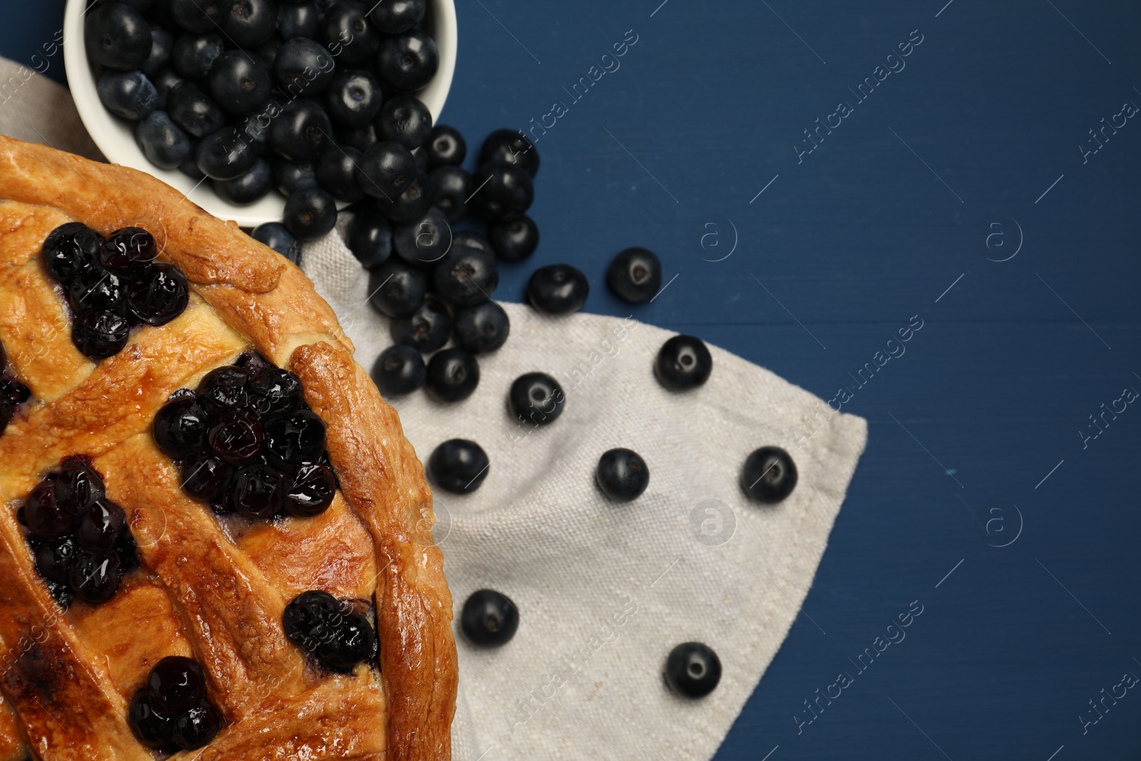 Photo of Tasty homemade pie with blueberries on blue wooden table, flat lay. Space for text