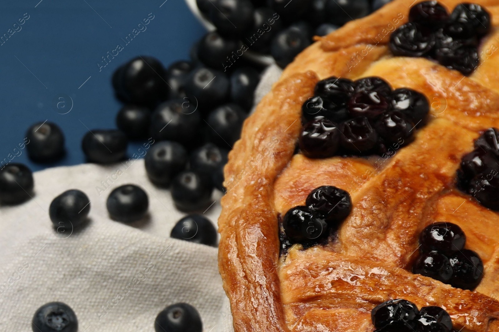 Photo of Tasty homemade pie with blueberries on blue table, closeup. Space for text