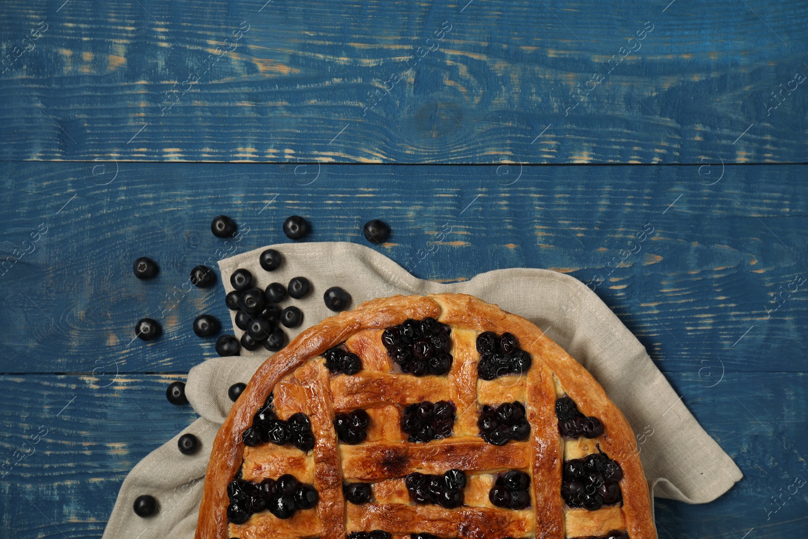 Photo of Tasty homemade pie with blueberries on blue wooden table, flat lay. Space for text