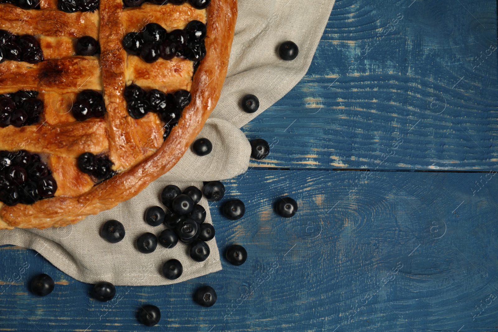 Photo of Tasty homemade pie with blueberries on blue wooden table, flat lay. Space for text