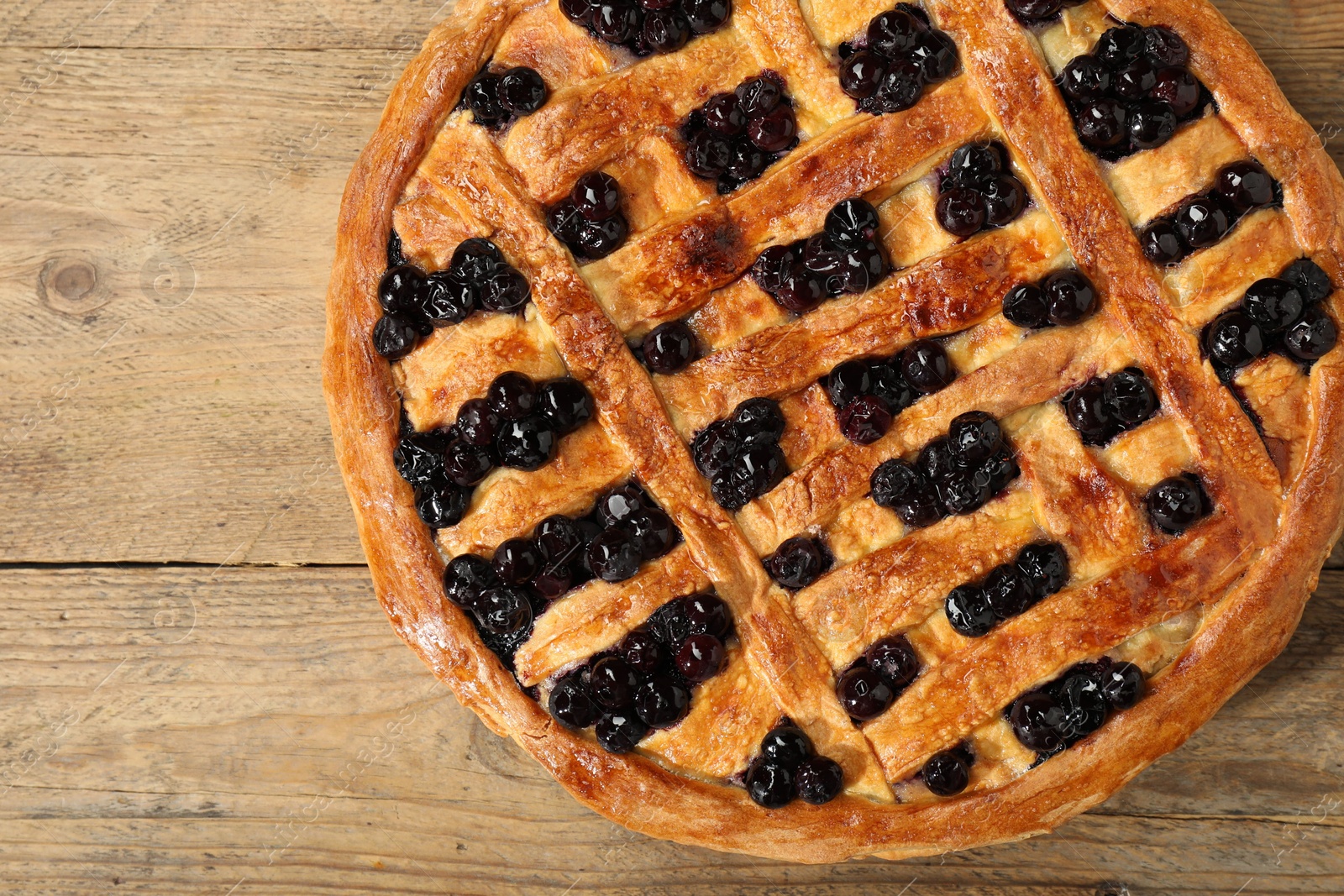 Photo of Tasty homemade pie with blueberries on wooden table, top view