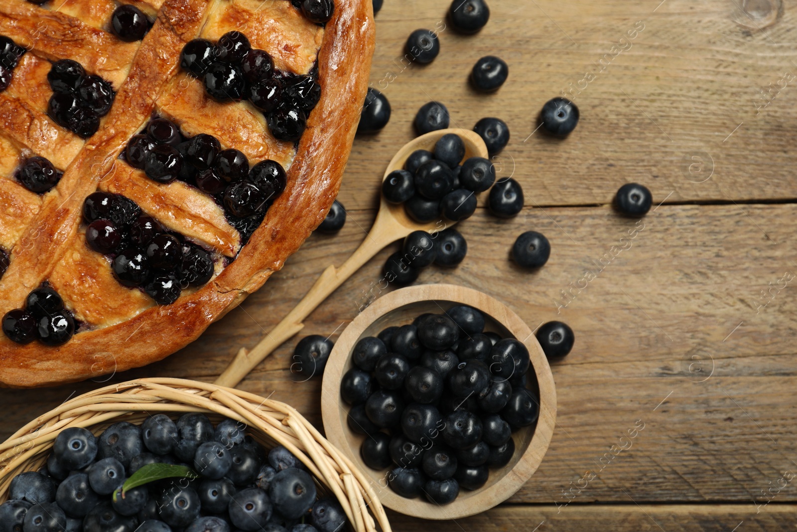 Photo of Tasty homemade pie with blueberries served on wooden table, flat lay