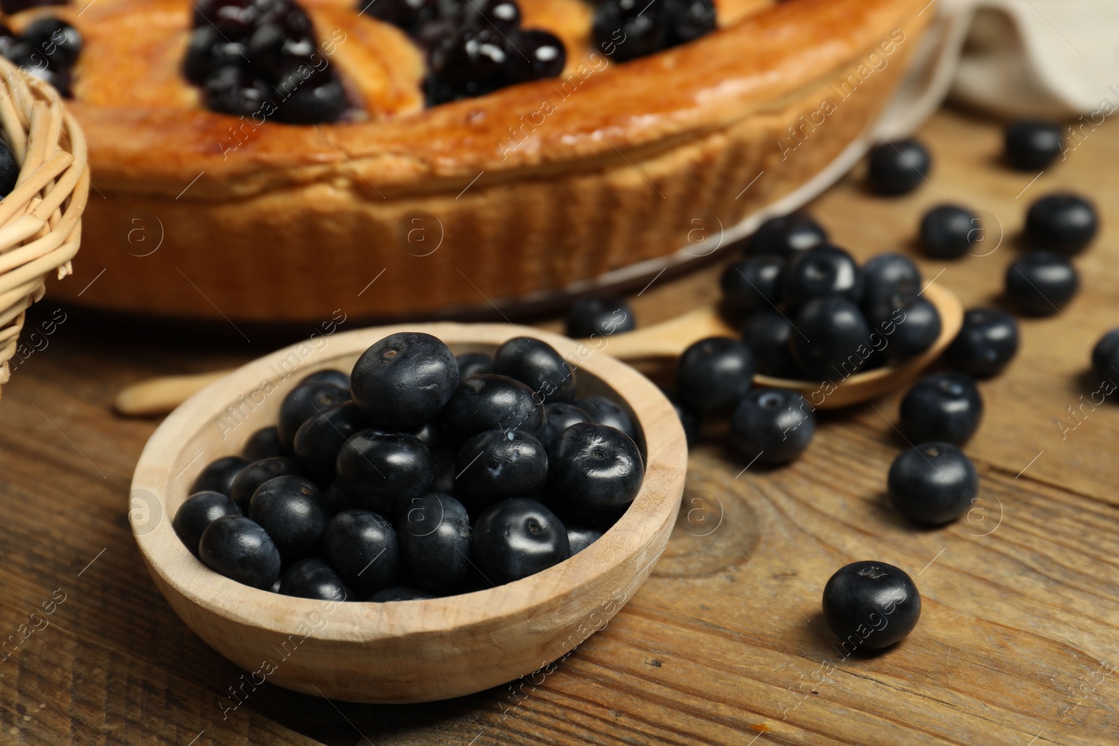 Photo of Fresh blueberries and tasty homemade berry pie on wooden table, closeup