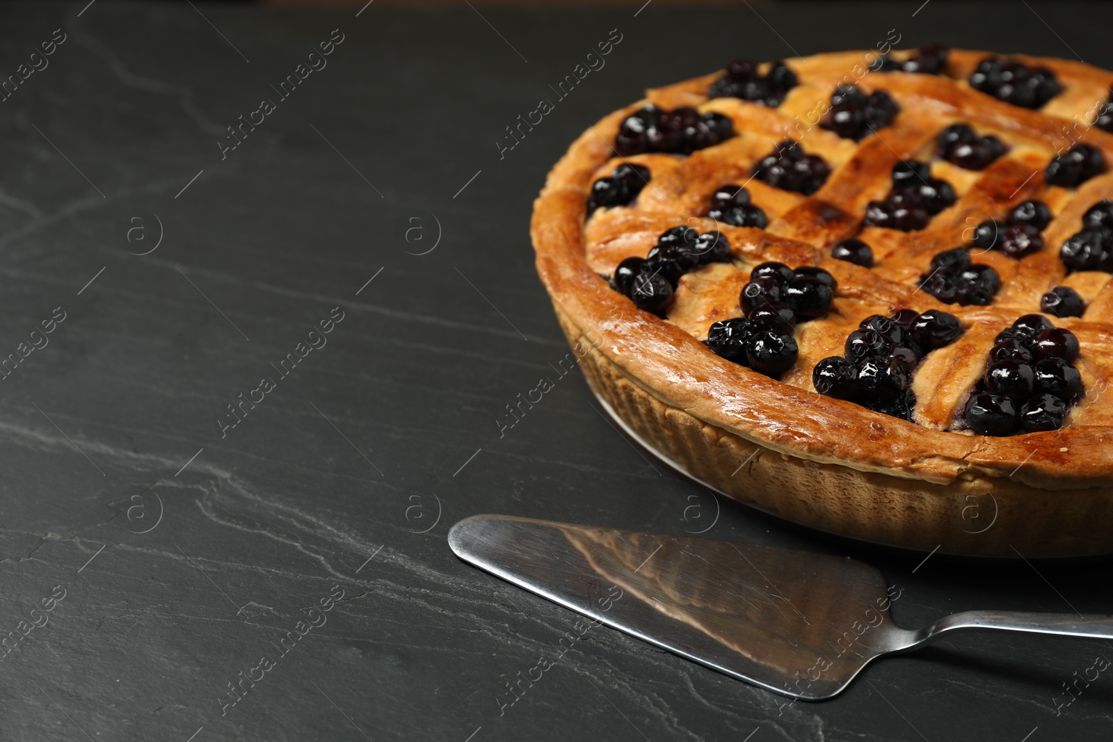 Photo of Tasty homemade pie with blueberries served on grey textured table, closeup. Space for text