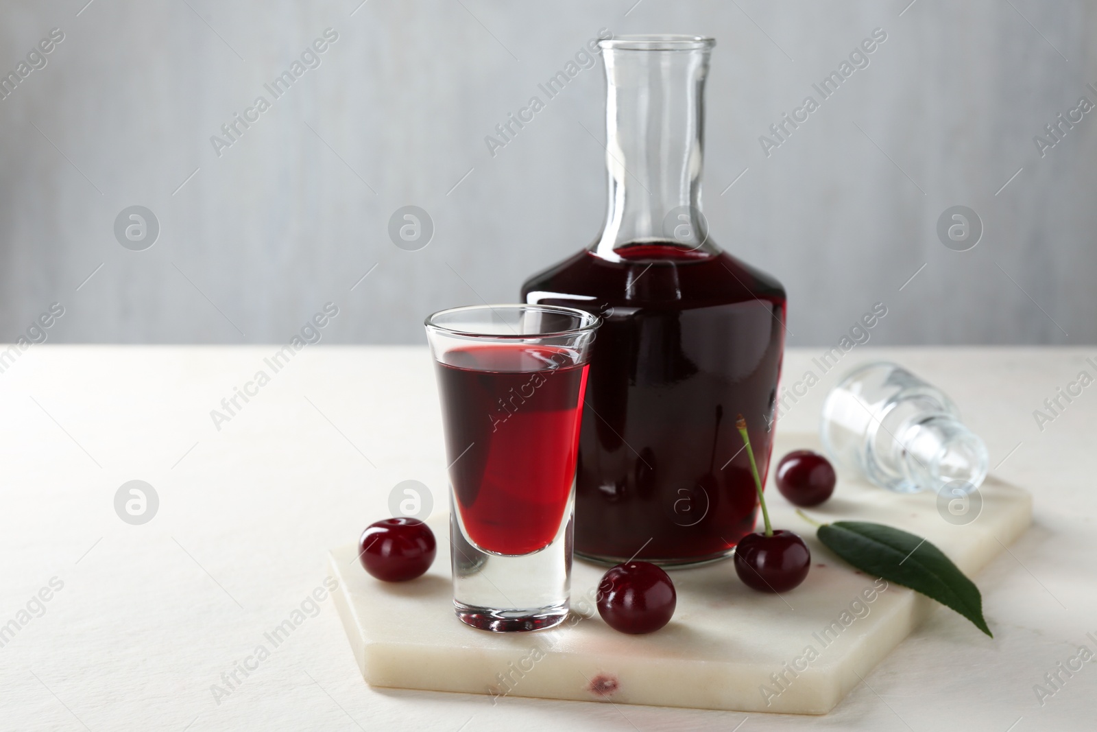 Photo of Delicious cherry liqueur and berries on white table. Space for text