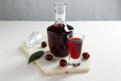 Photo of Delicious cherry liqueur and berries on white table