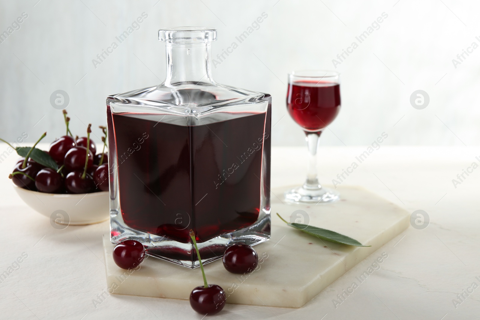 Photo of Delicious cherry liqueur and berries on white table