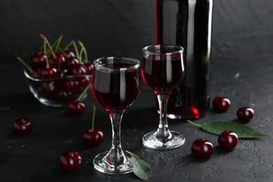 Delicious cherry liqueur and berries on black table