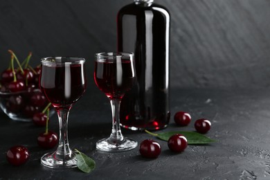 Photo of Delicious cherry liqueur and berries on black table