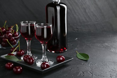 Photo of Delicious cherry liqueur and berries on black table