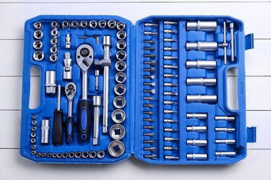 Photo of Auto mechanic's tools in plastic box on white wooden table, top view