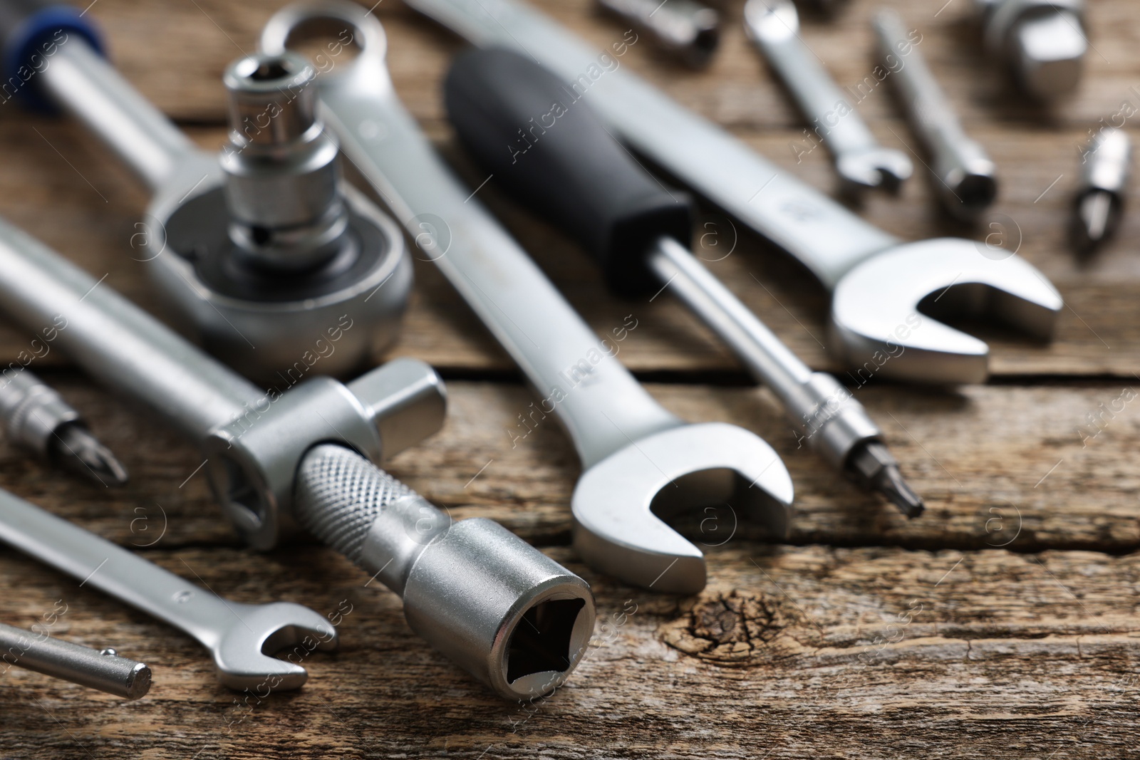 Photo of Different auto mechanic's tools on wooden table, closeup